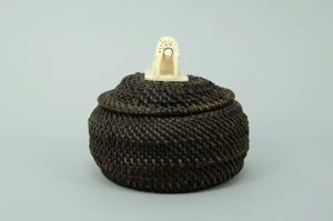 Image: round baleen basket with walrus head finial, tusks carved to touch base 